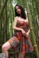 A woman in a colorful dress posing in a bamboo forest.