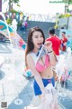 A woman in a bikini standing in front of a water fountain.