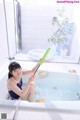 A woman sitting in a bathtub holding a green tube.