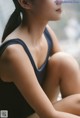 A woman in a black leotard sitting on a window sill.