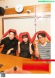 A group of people sitting around a table with red pillows on their heads.