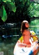 A woman in a bikini paddling a kayak on a river.