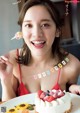 A woman in a red bikini holding a fork in front of a birthday cake.