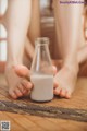 A person holding a glass bottle of milk on the floor.